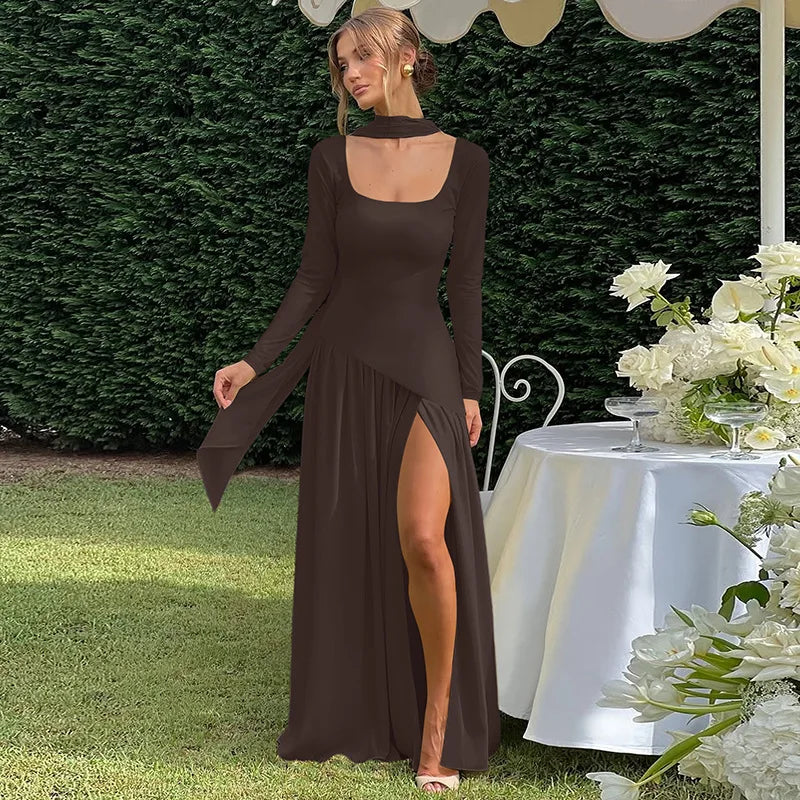 Woman in a long black dress standing outdoors with a table and flowers in the background