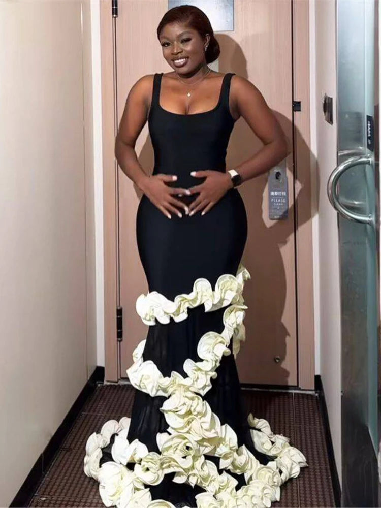 Woman in a black evening gown with floral details standing in a hallway.