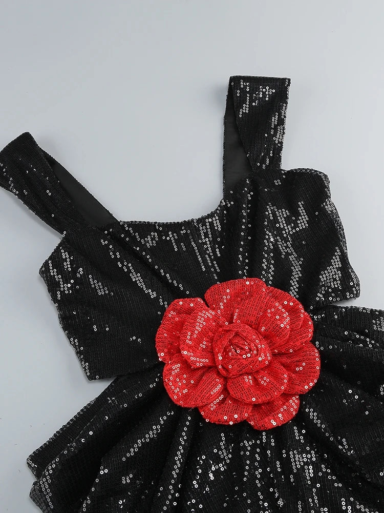 Black sequined dress with a red floral embellishment on a light gray background