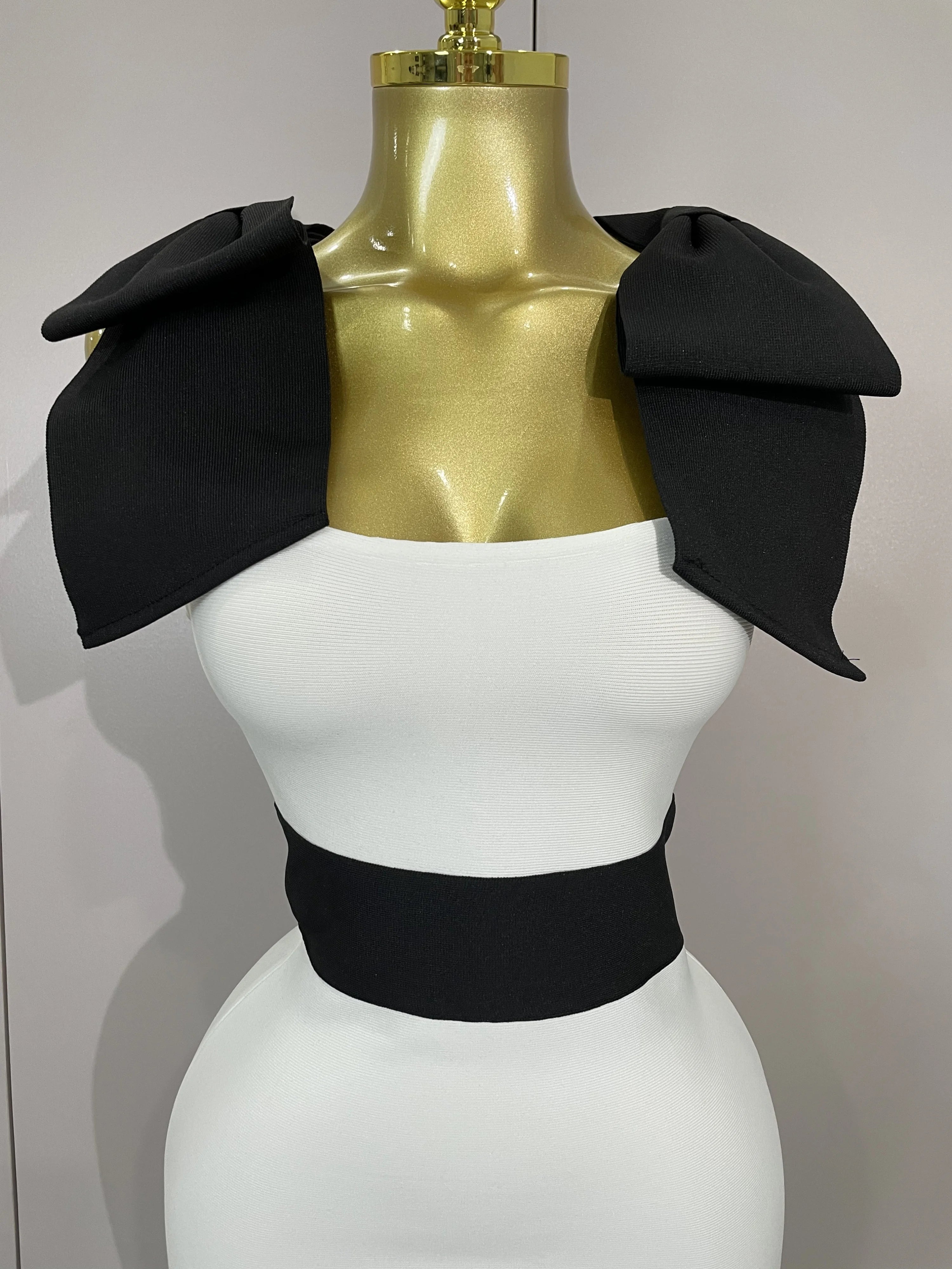 Mannequin wearing a black and white outfit with a gold top on a plain background