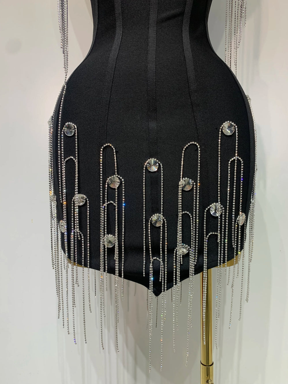Black dress with silver fringe and embellishments on a mannequin against a white background