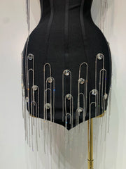Black dress with silver fringe and embellishments on a mannequin against a white background
