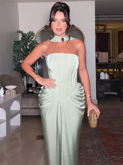Woman in a light green strapless dress holding a clutch in an indoor setting.