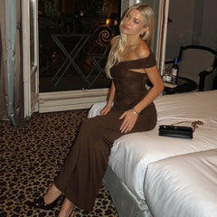 Woman in a brown dress sitting on a bed in a room with leopard print carpet.