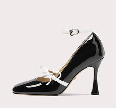 Black high-heeled shoe with white bow on a light gray background