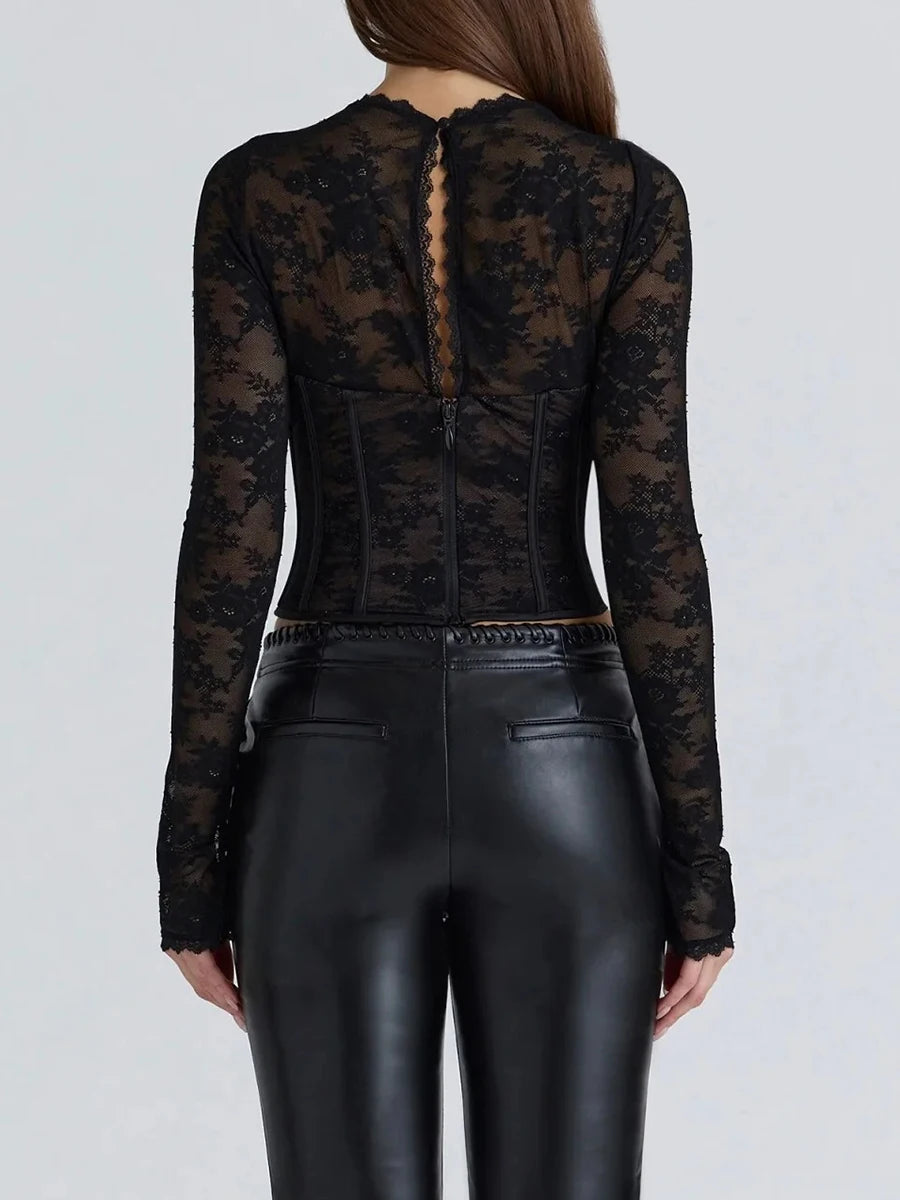 Person wearing a black lace top and black leather pants on a light gray background