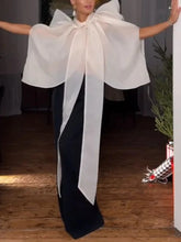 Sheer organza turtleneck top with a large bow and voluminous sleeves, paired with black trousers.