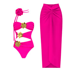 Pink one-piece swimsuit with cutouts and gold flower accents, paired with a matching flowing skirt.