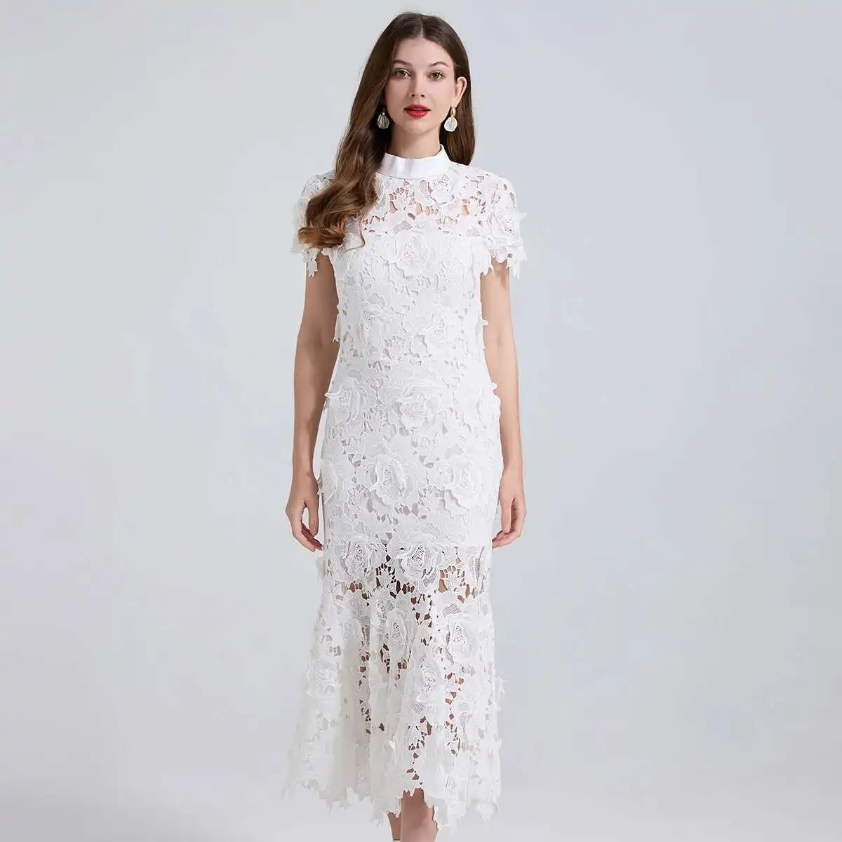 Woman wearing a white lace dress against a plain background