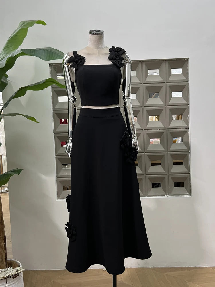 Black dress with floral details on a mannequin against a white wall.