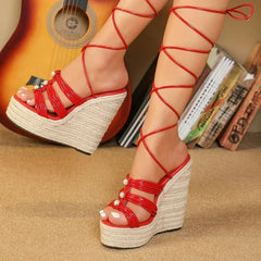 Red strappy wedge sandals on a beige surface with a guitar and books in the background.