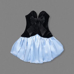 Black velvet top with a large bow and light blue skirt on a gray background