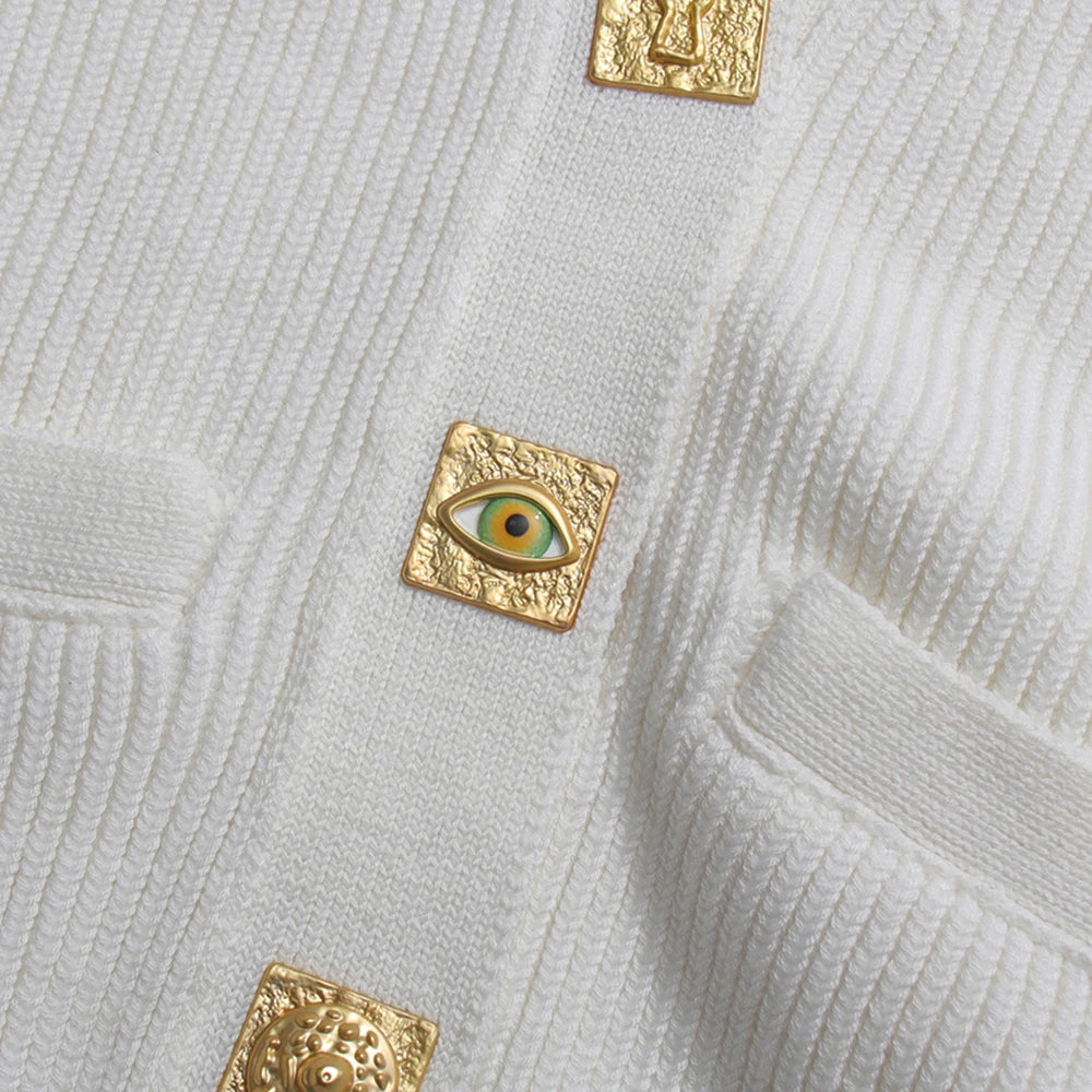 Gold square brooches with eye design on a textured light gray fabric background