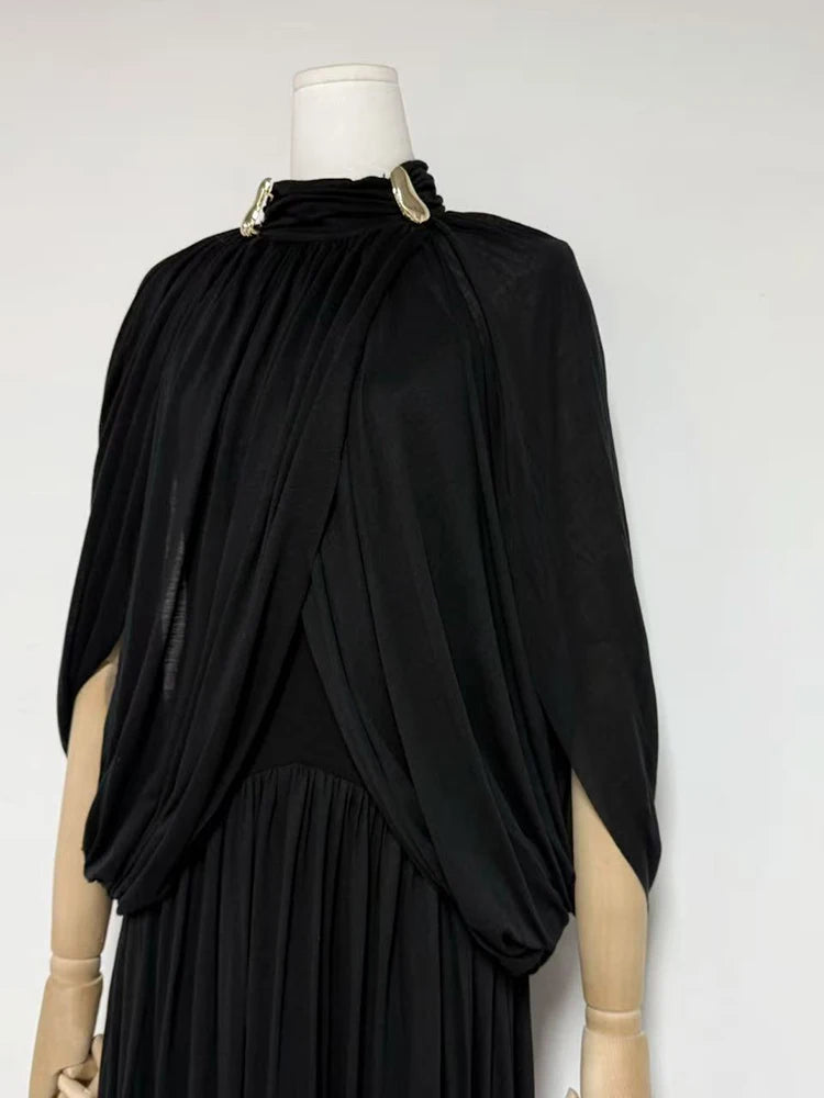 Black draped dress on a mannequin against a white background