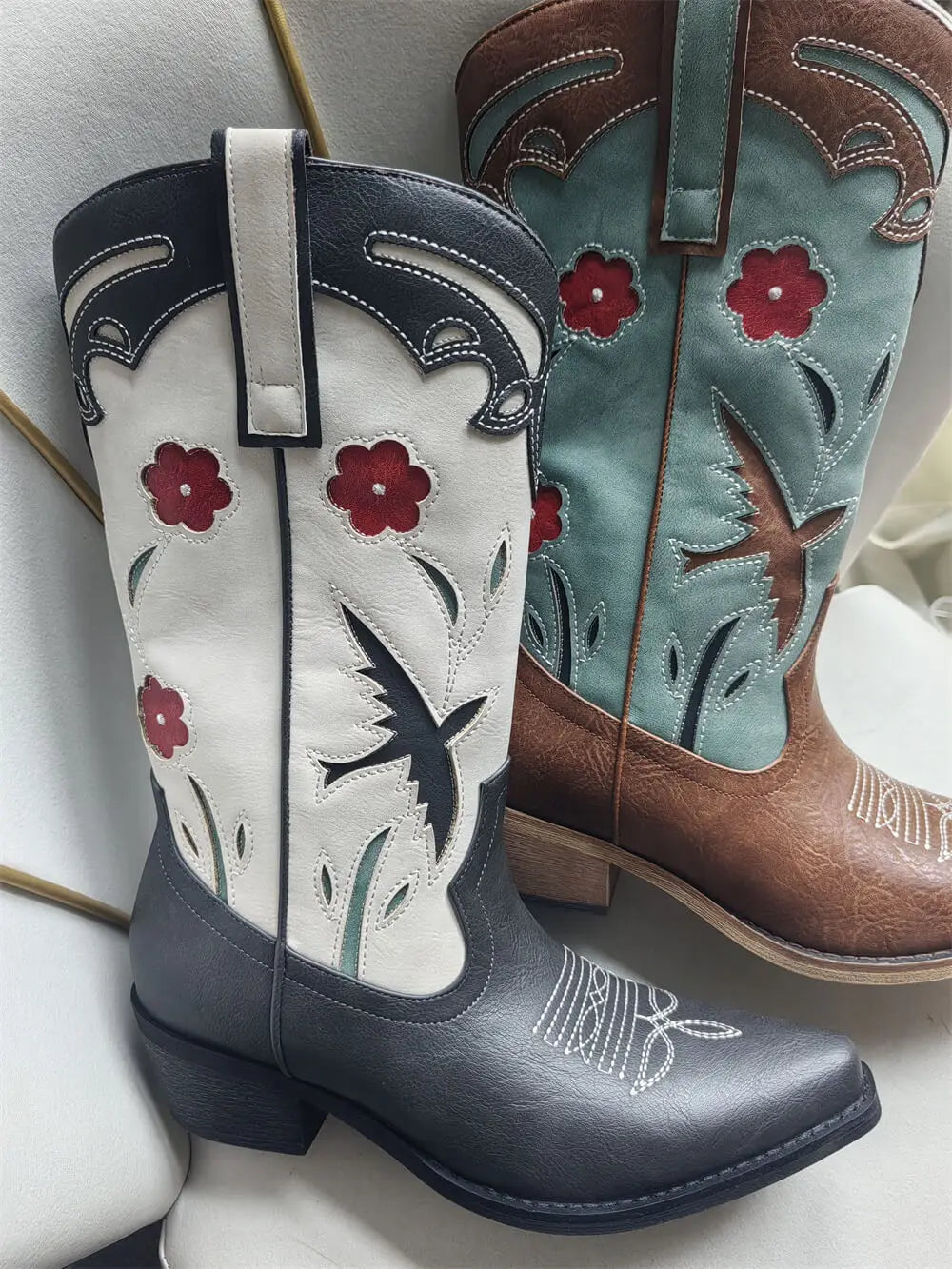 Pair of cowboy boots with floral and star designs on a light background