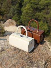 White and brown leather top handle bags on rocks