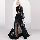 Woman wearing a black lace outfit holding a handbag in a white archway