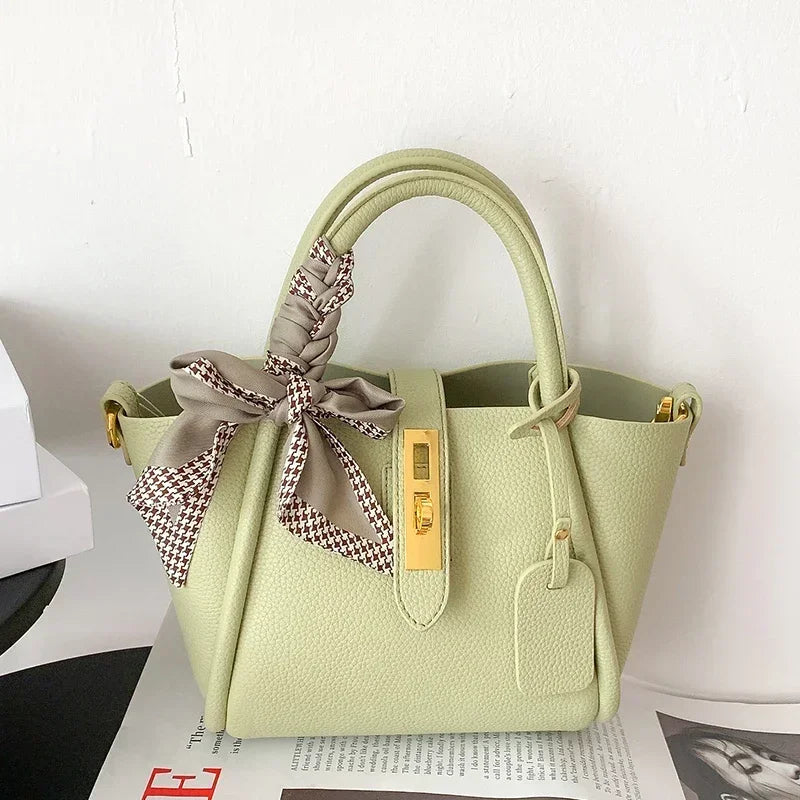 Light green handbag with a decorative bow on a white background