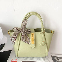 Light green handbag with a decorative bow on a white background