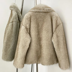 Beige faux fur coat on a rack against a white background