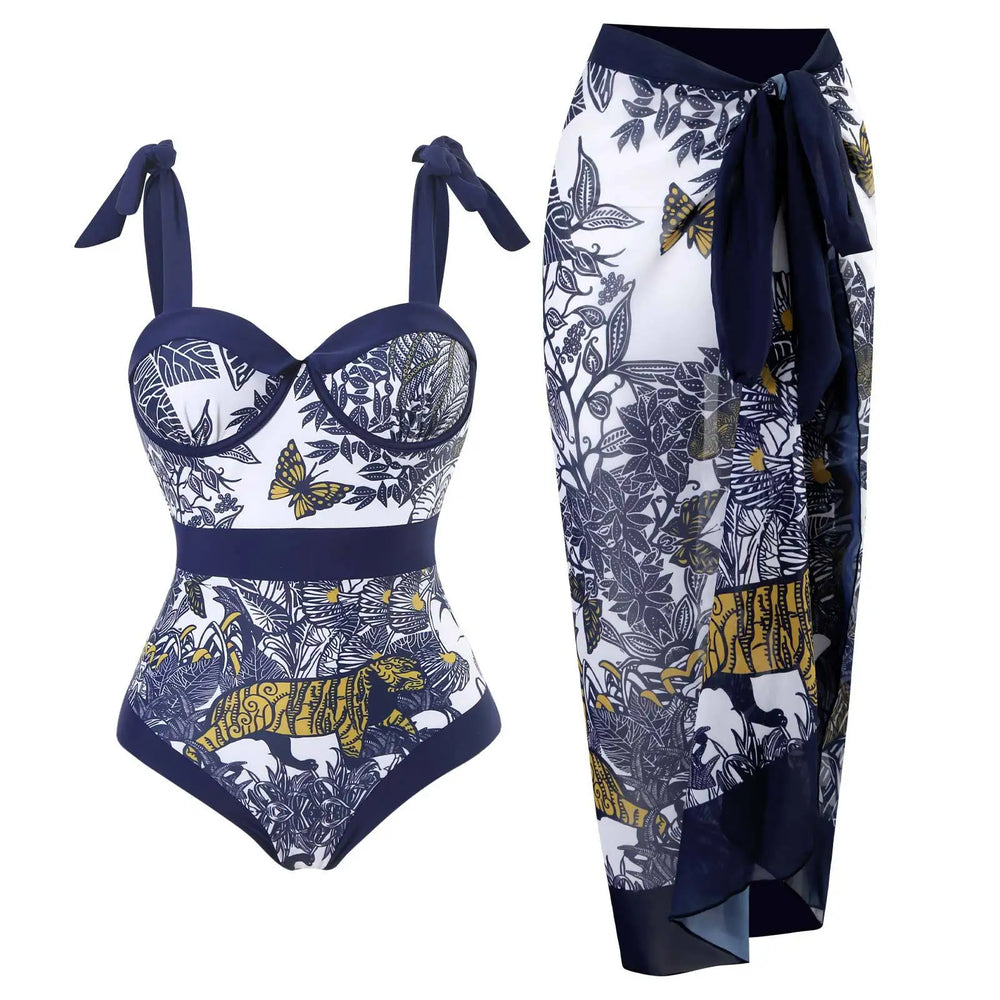 Navy and white printed one-piece swimsuit with underwire support and tie straps, alongside a matching sarong.