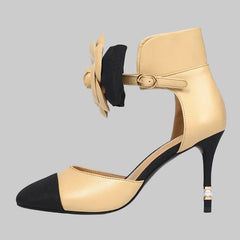 Beige and black high-heeled shoe with floral detail on a white background