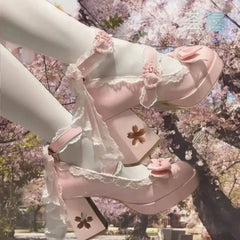 Pastel pink sandals with floral details worn by a person against a cherry blossom background
