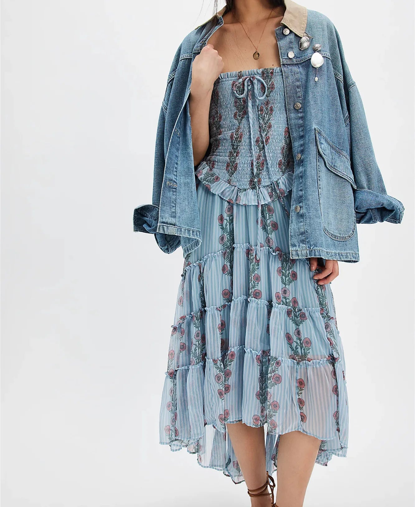 Woman wearing a floral dress with a denim jacket on a white background