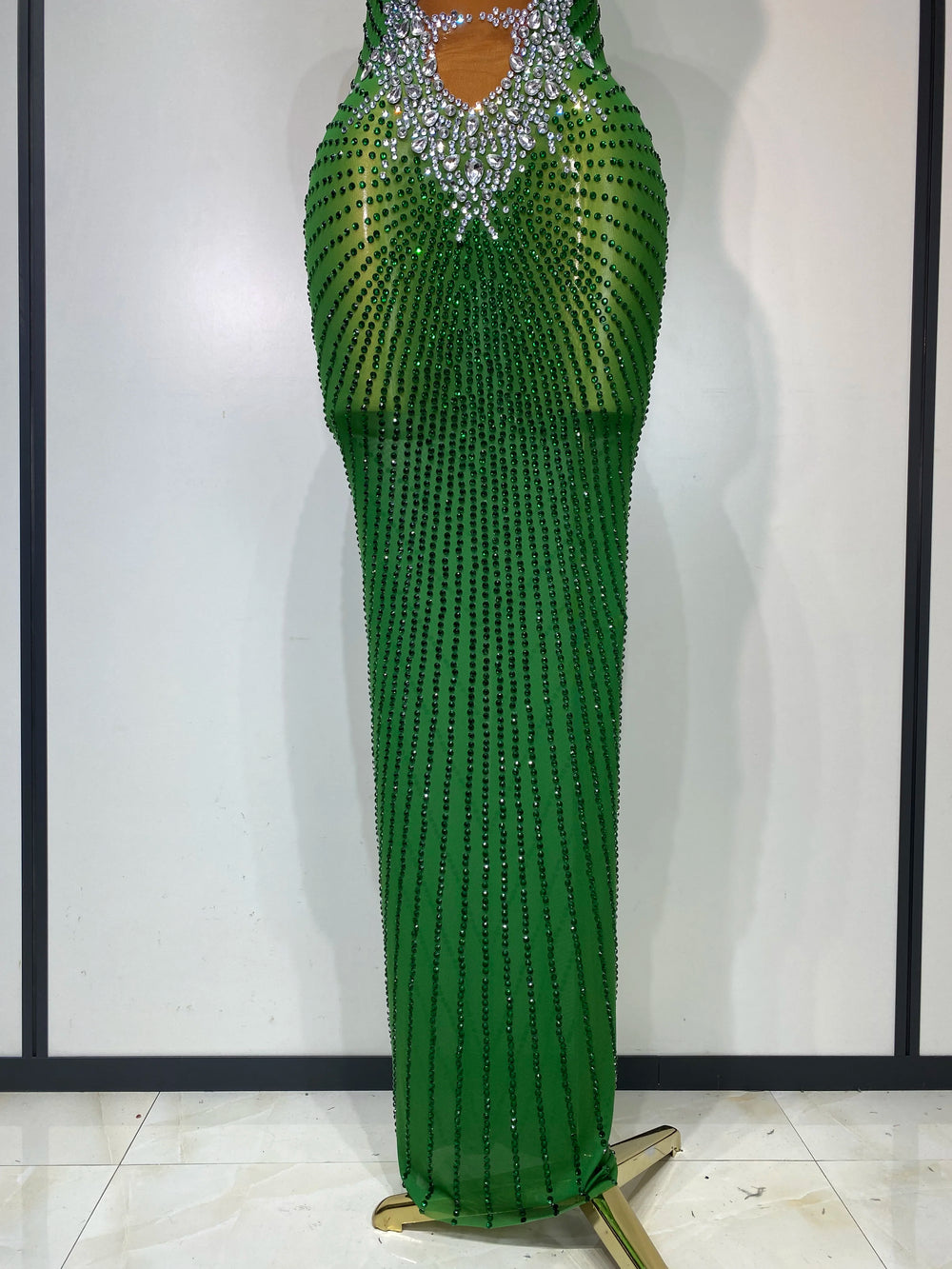 Green beaded evening gown on a mannequin against a white background