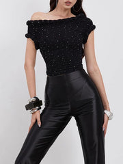 Woman wearing a black off-shoulder top with sequins and black pants