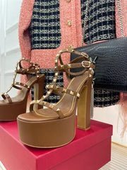 Gold platform sandals on a red box with a patterned background