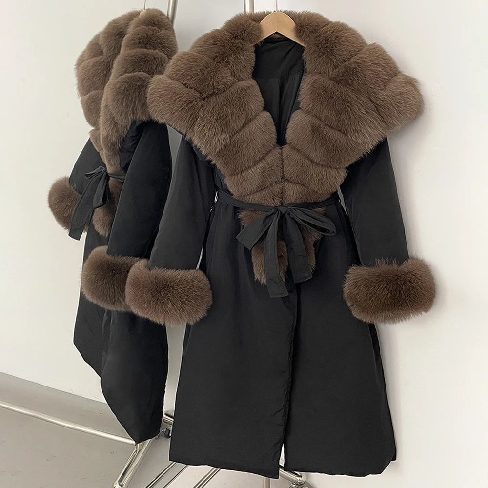 Black coat with brown fur trim on a hanger against a white background