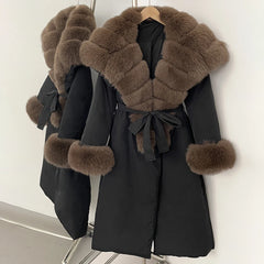 Black coat with brown fur trim on a hanger against a white background