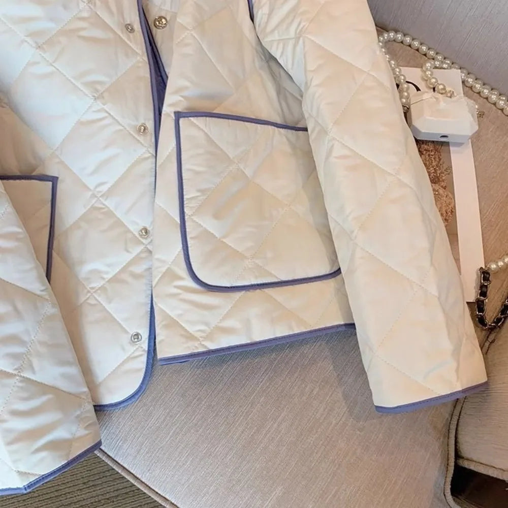 white quilted jacket with purple trim on a wooden surface