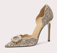 Sparkling high-heeled shoe with a decorative bow on a light gray background