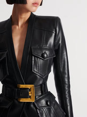 Black leather outfit with a gold belt buckle on a plain background