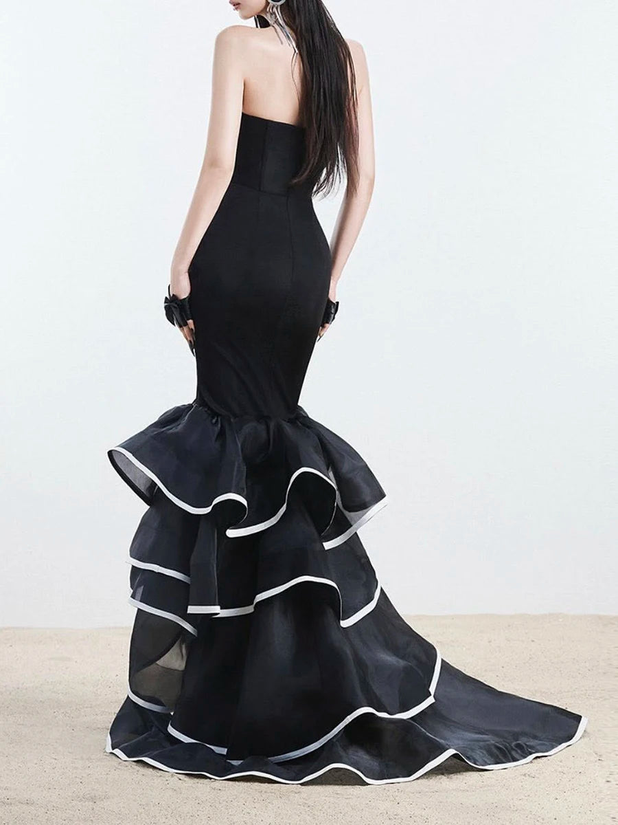 Black strapless gown with ruffled layers on a plain background