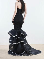 Black strapless gown with ruffled layers on a plain background