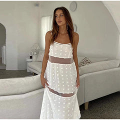 Woman wearing a white polka dot dress in a modern bedroom setting