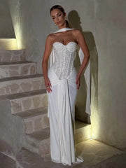 Woman in a white strapless gown standing on stone steps.