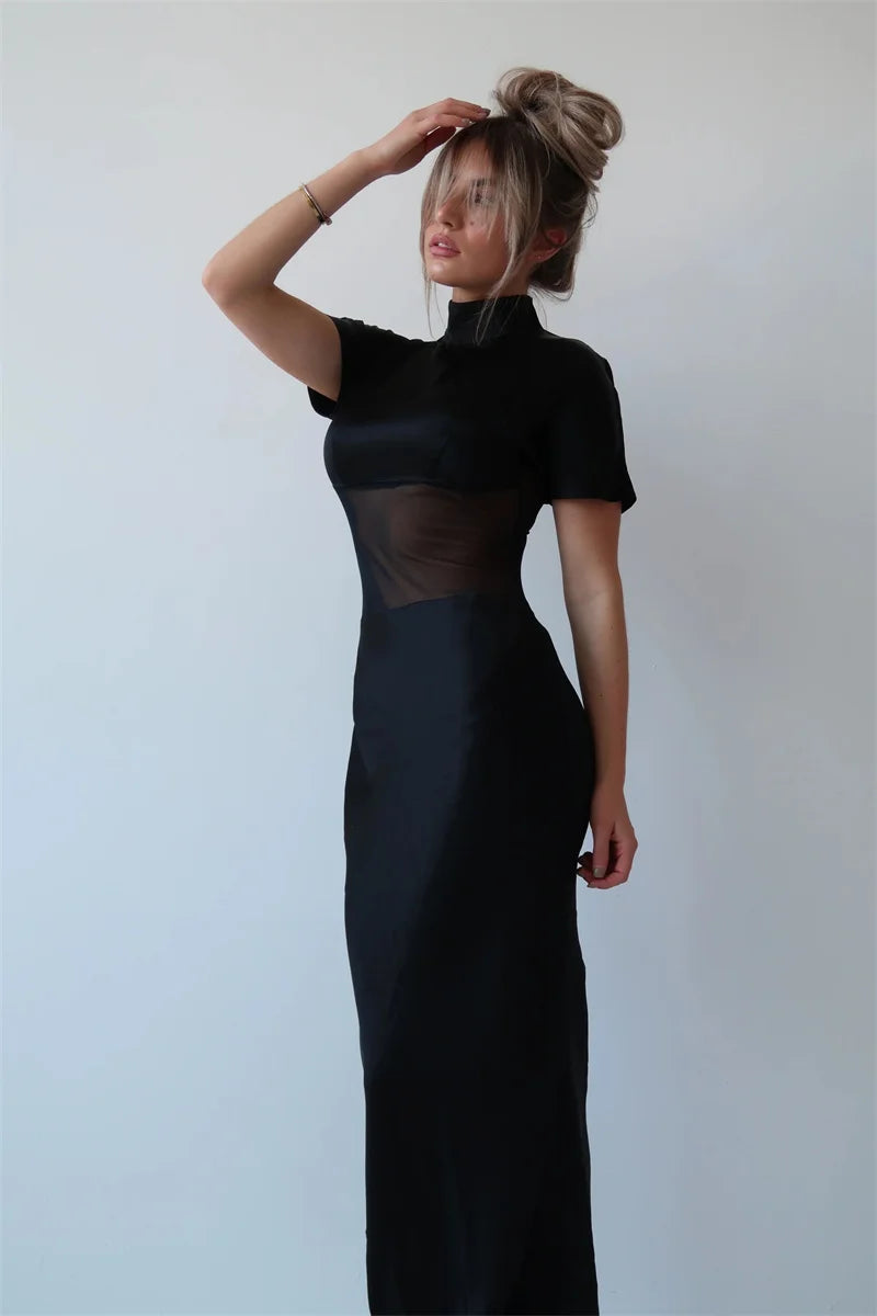 Woman wearing a black dress with sheer panels against a white background