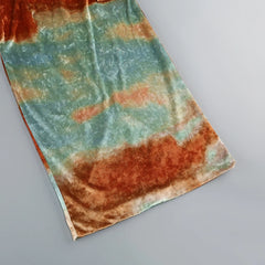 Tie-dye fabric with orange and green patterns on a gray background
