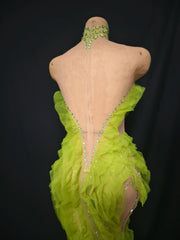 Mannequin wearing a bright green dress with embellishments on a black background
