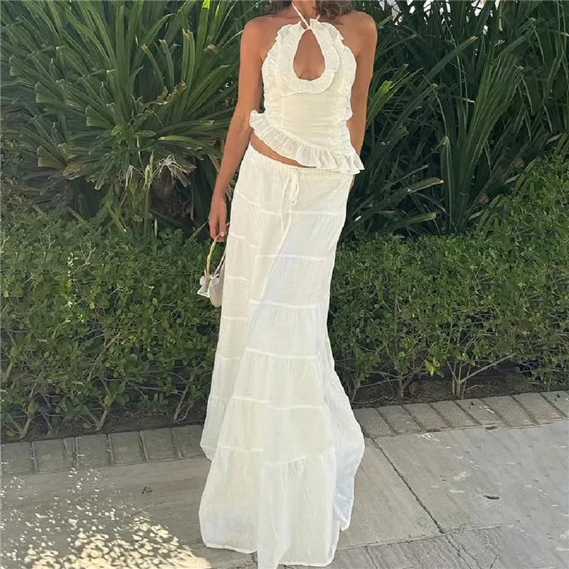 Woman wearing a white ruffled dress standing outdoors with greenery in the background