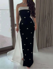 Woman wearing a strapless black and white dress with floral patterns indoors.