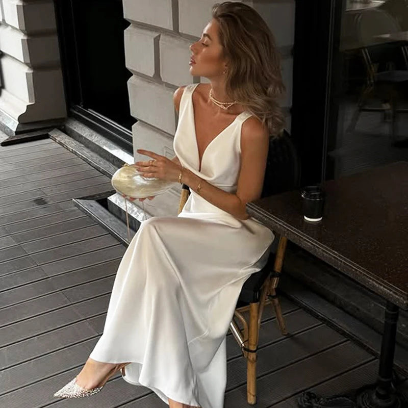 Woman in a white dress sitting on a chair outdoors.