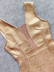 Gold swimsuit top on a gray background