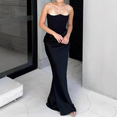 Woman wearing a black strapless gown standing in an indoor setting.