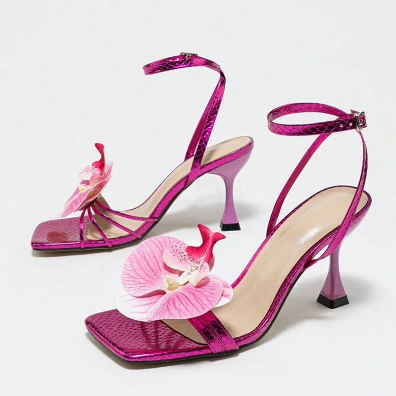 Pink high-heeled shoes with floral decorations on a light gray background