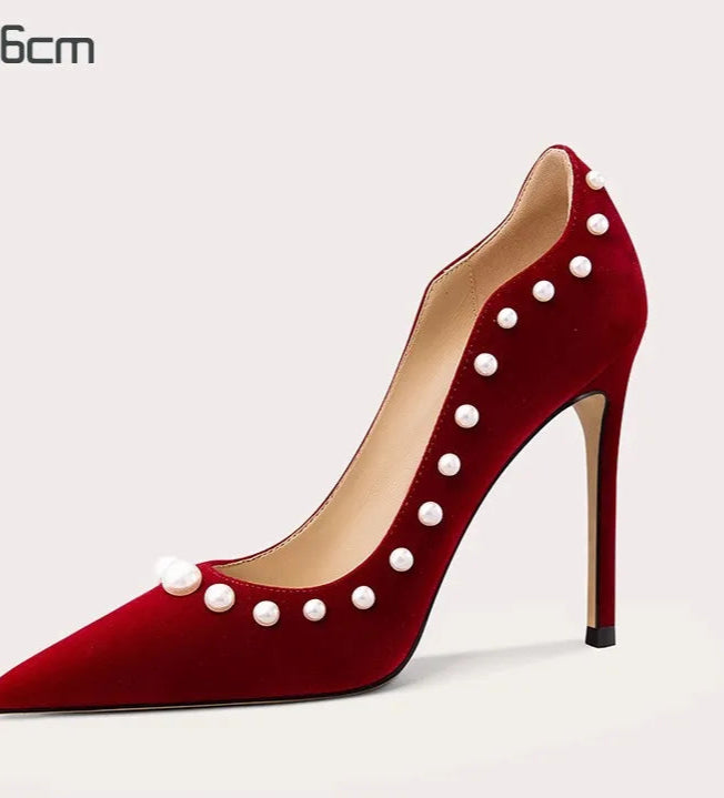 Red high-heeled shoe with pearl embellishments on a white background